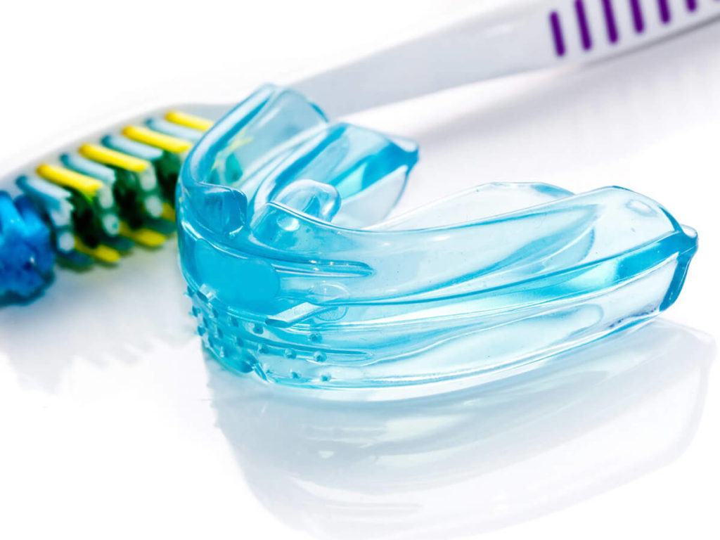 image of a mouth guard next to a tooth brush