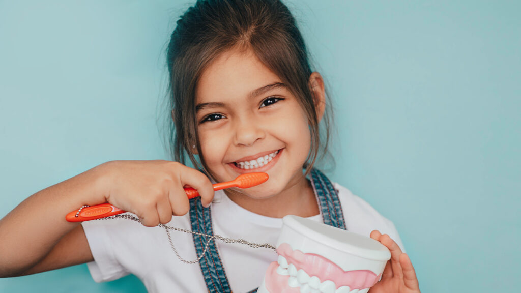 image of a girl holding a tooth brush and smiling