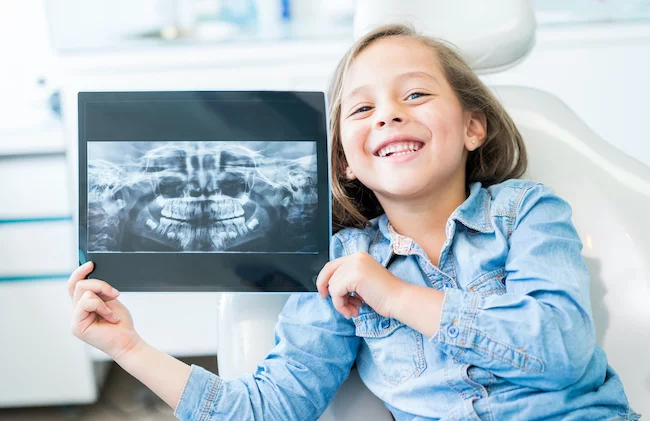 little girl holding a dental x-ray