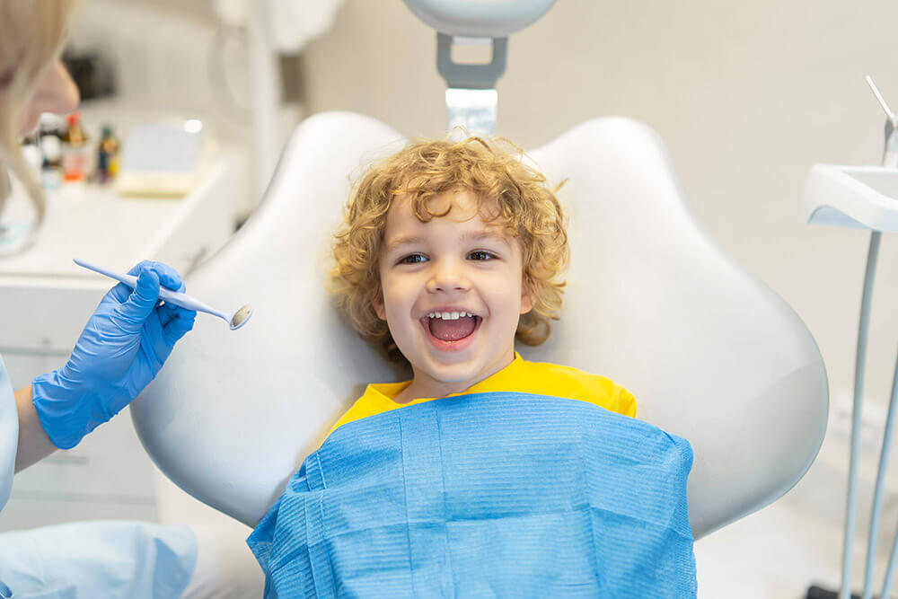 little boy smiling in a dental chair
